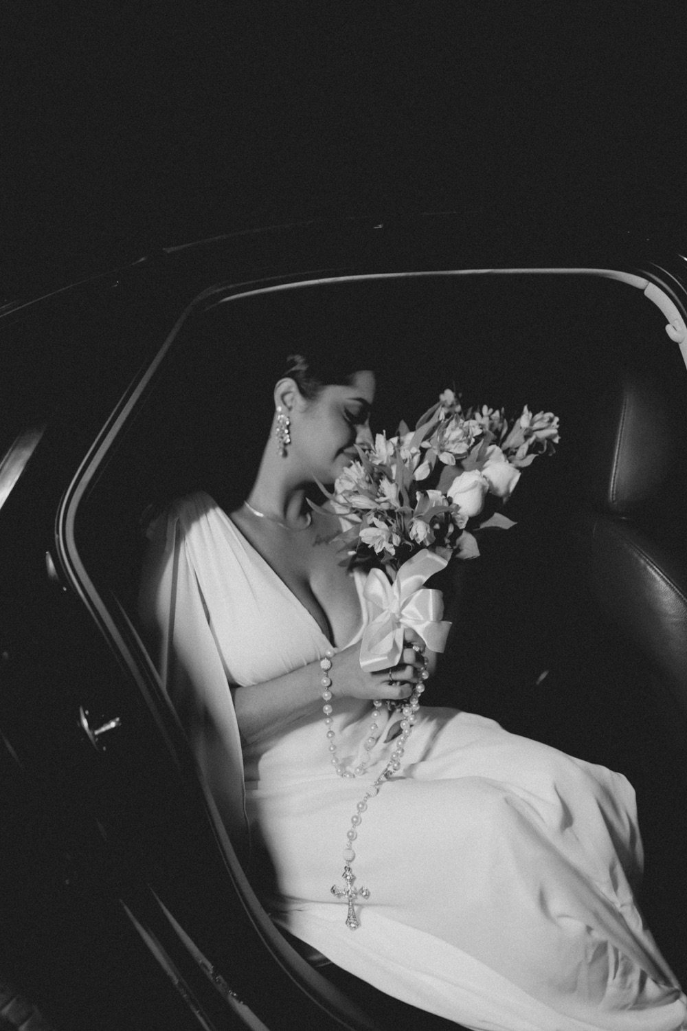 Bride in the back of the car with her bouquet and rosary